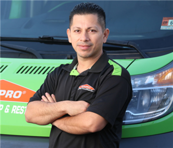 man with short black hair standing in front of a green truck